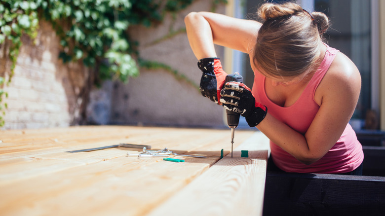 woman drilling wood outside as she builds a patio