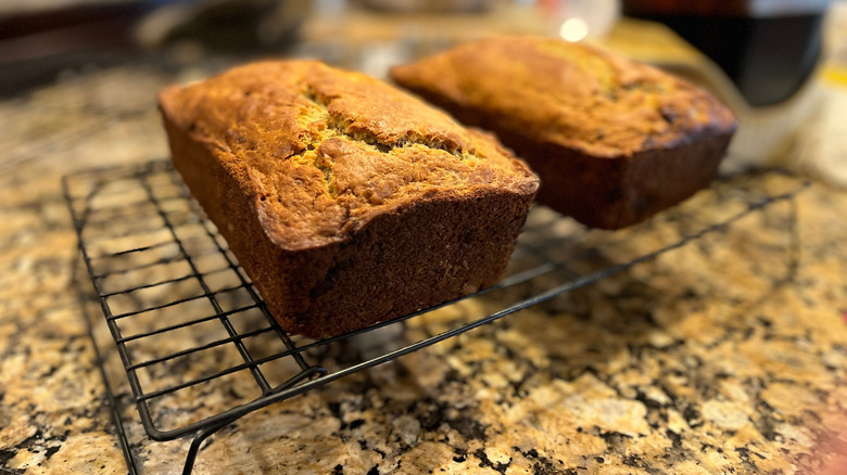 Two loaves of bread on top of a brown countertop in kitchen