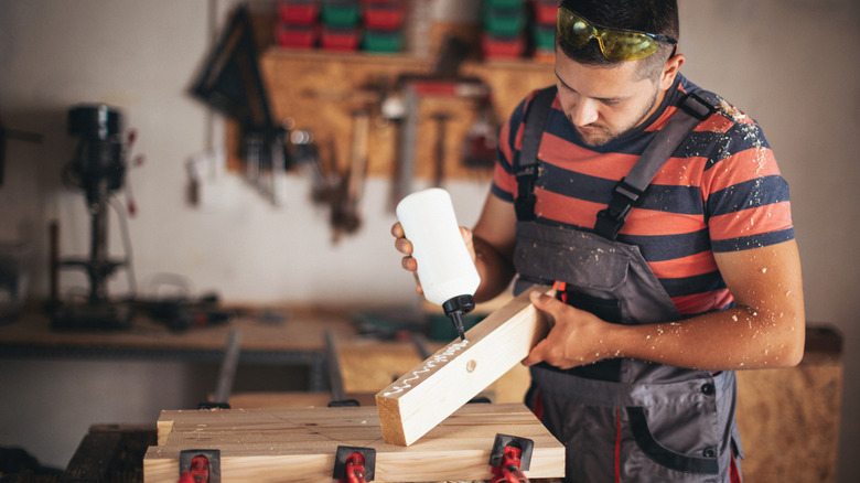 Young carpenter applying glue to a piece of wood