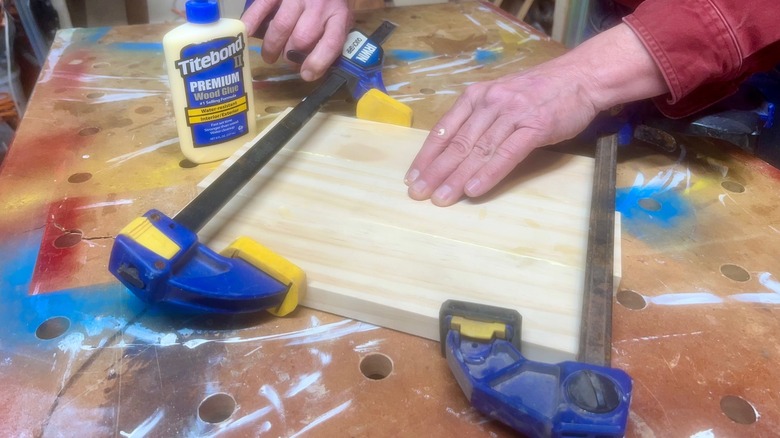 Up close photo of two hands using tools and glue to clamp wood together