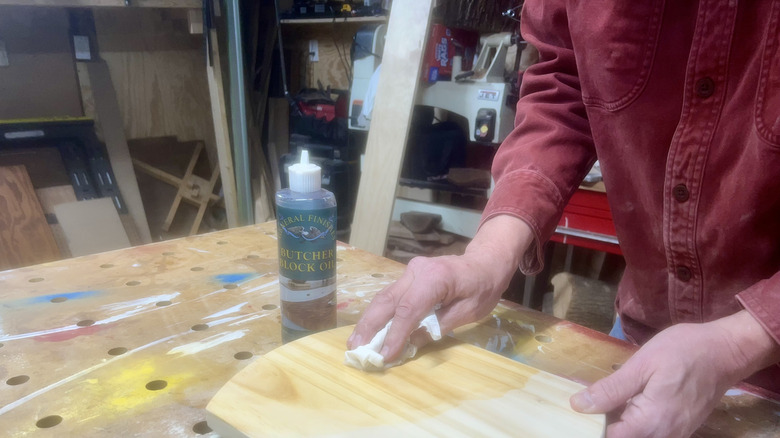 a person wiping mineral oil on cutting board