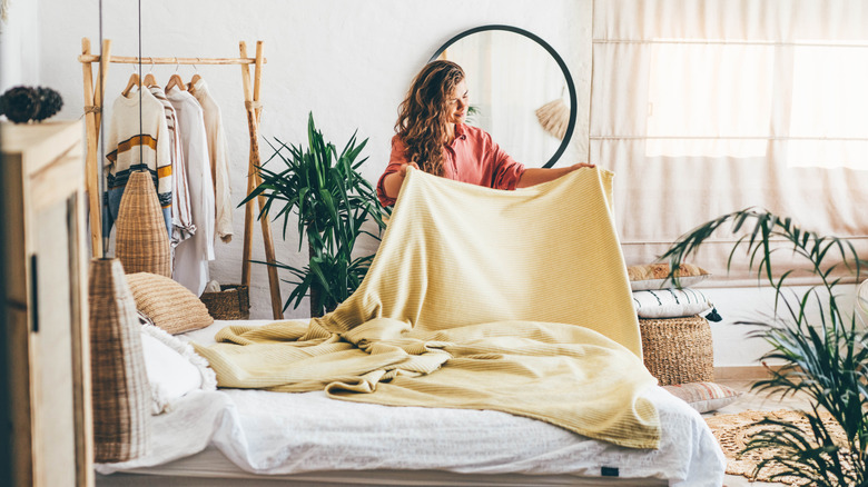 woman making bed in boho bedroom