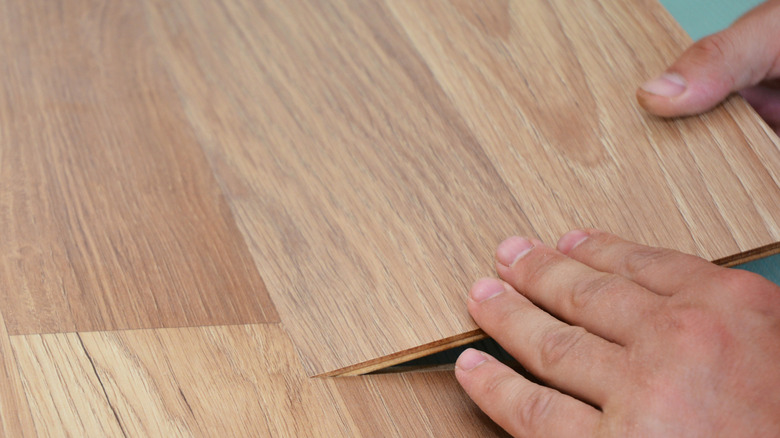 close up of hands installing flooring