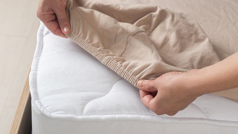 Woman putting sheets on bed