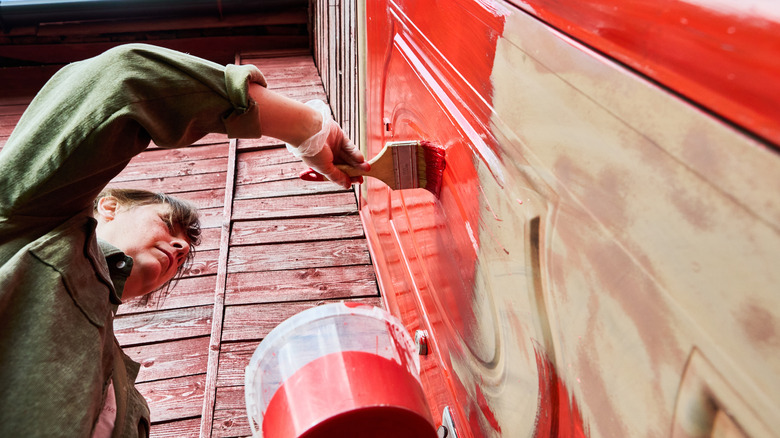 woman painting wooden door red