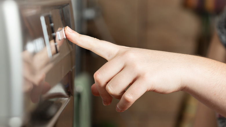 person touching closed dishwasher