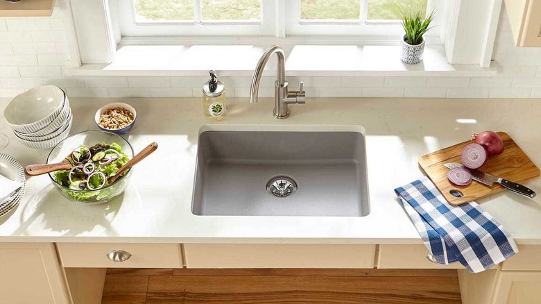 wheelchair-accessible roll-under kitchen sink under window with quartz countertops and beige cabinets