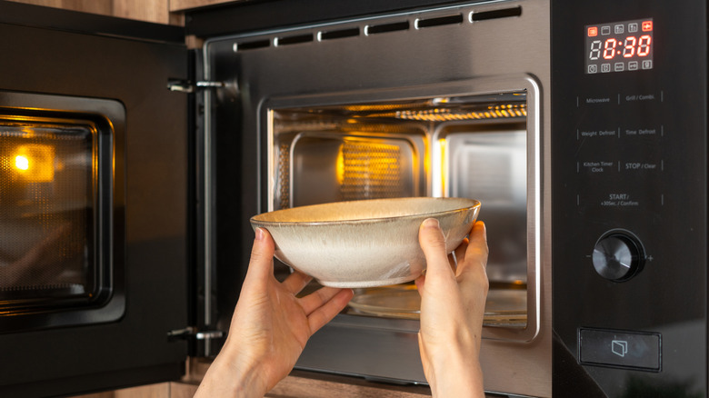 Hands placing bowl in microwave