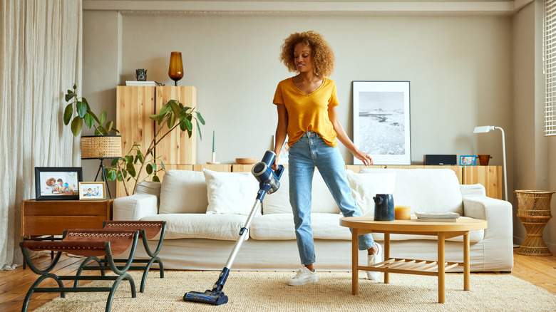 woman cleaning a carpet with a cordless vacuum