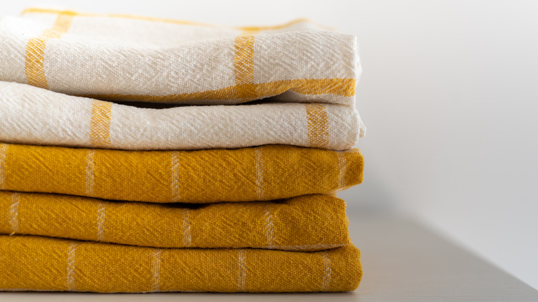 A neatly folded pile of yellow and white dish towels