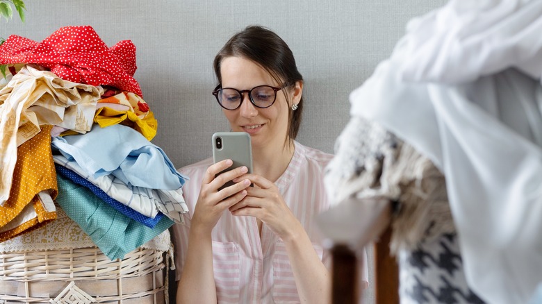 woman on phone with laundry pile