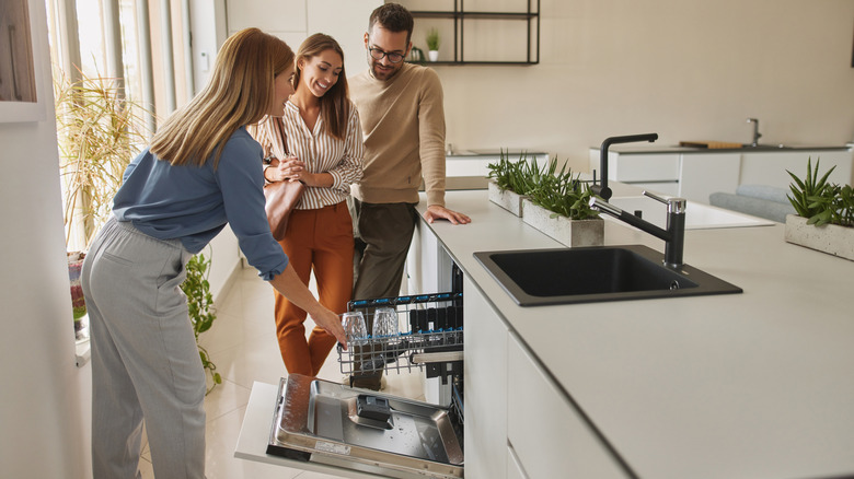 assistant showing a couple a dishwasher in a home improvement or appliance store