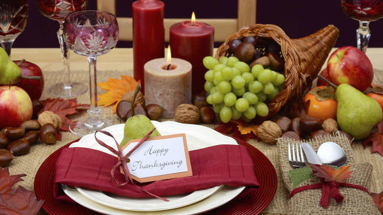 fall table setting with cornucopia centerpiece on thanksgiving table