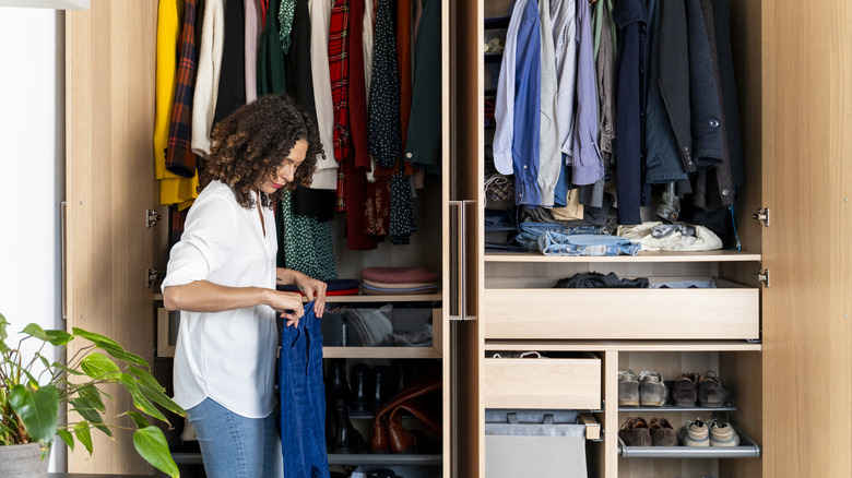 woman organizing closet and folding a pair of jeans