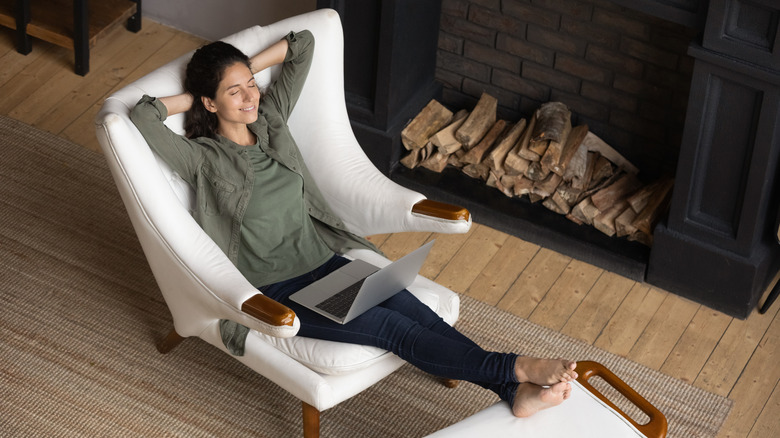 A woman sitting in a chair in front of a fireplace