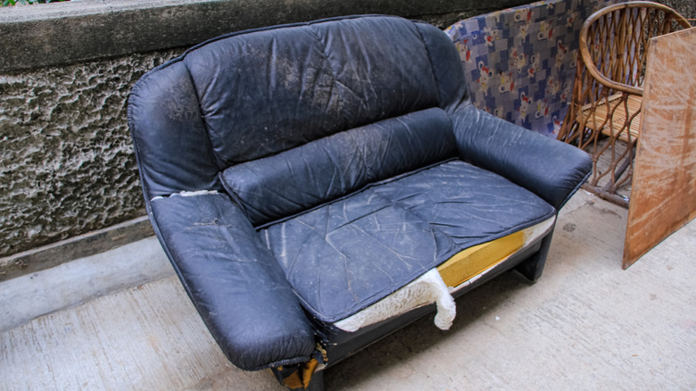 old blue couch on the street with damage