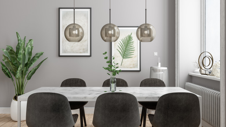 Dining room with gray walls, charcoal dining chairs, marble top dining table, and three hanging pendants