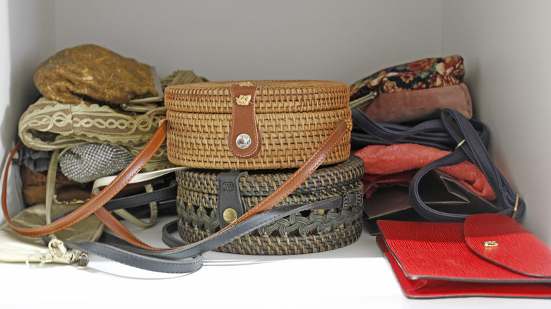 messy pile of handbags on a white closet shelf