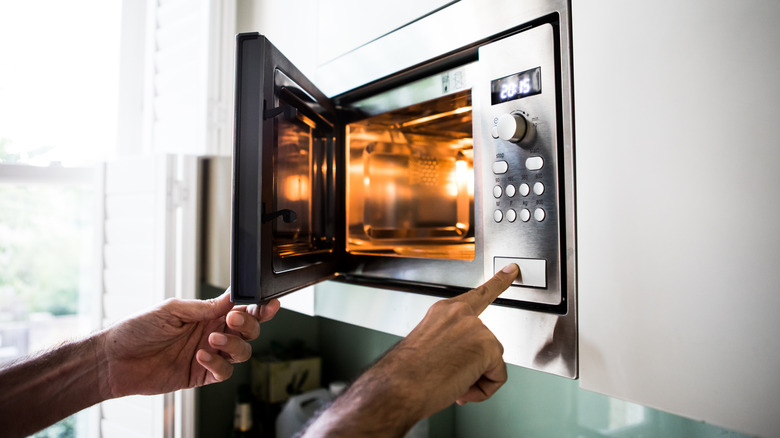 hands pressing buttons microwave oven