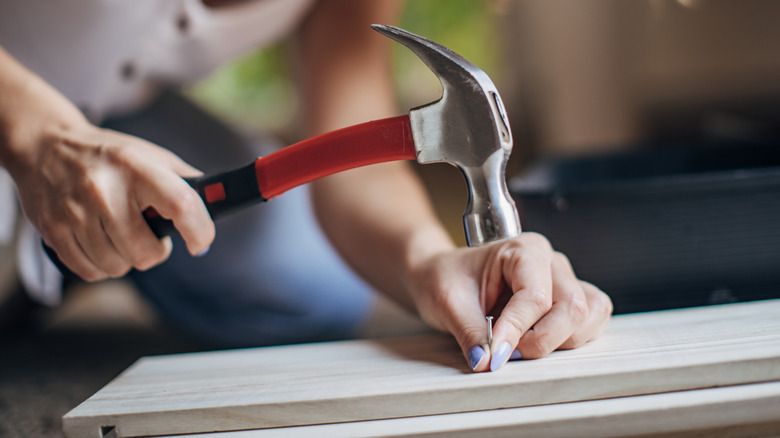 Woman hammering a nail into a board