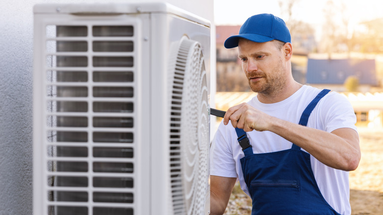 Man working on heat pump's outdoor unit