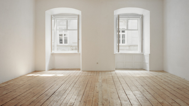 pine wood floors in an light-filled apartment that are halfway through being refinished, with the right side still to finish