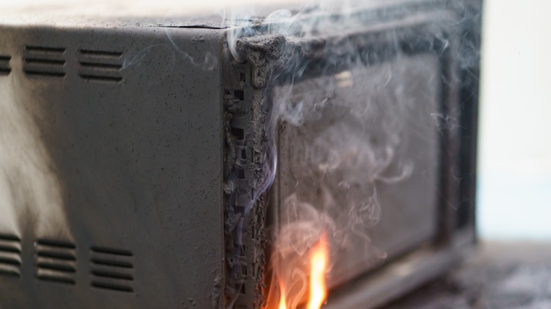 Microwave on fire with smoke all around