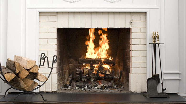 lit fireplace with stack of wood nearby