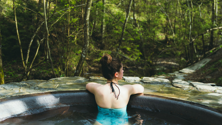 woman in stock tank pool in woods