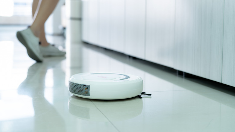 Robot vaccum cleaning the floor while homeowner walks around