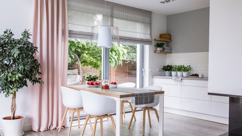 kitchen with a large glass sliding door with large gray Roman shades and floor-to-ceiling pink drapery