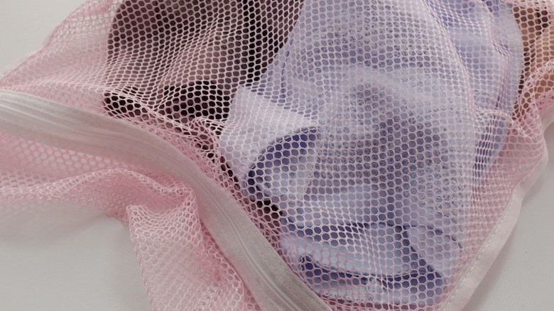 pink mesh laundry bag with dirty clothing items inside