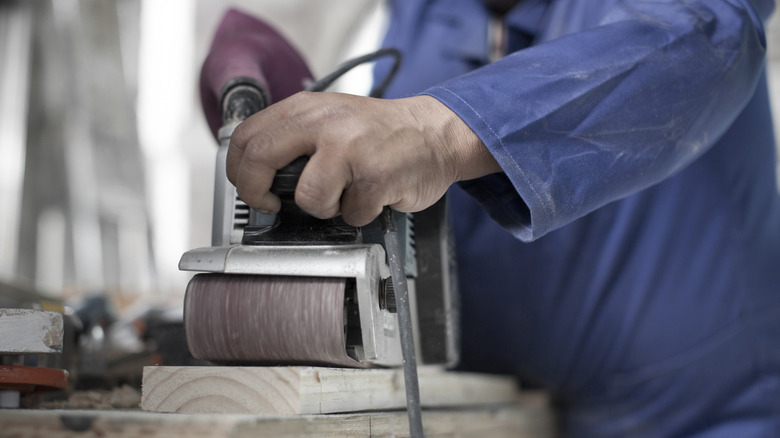 Sanding a board with a belt sander