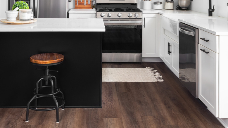 modern kitchen with white upper and perimeter cabinets, black island cabinets, white stone countertops, black hardware, and black plumbing fixtures