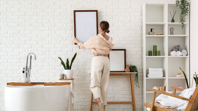 woman hanging frame in bathroom