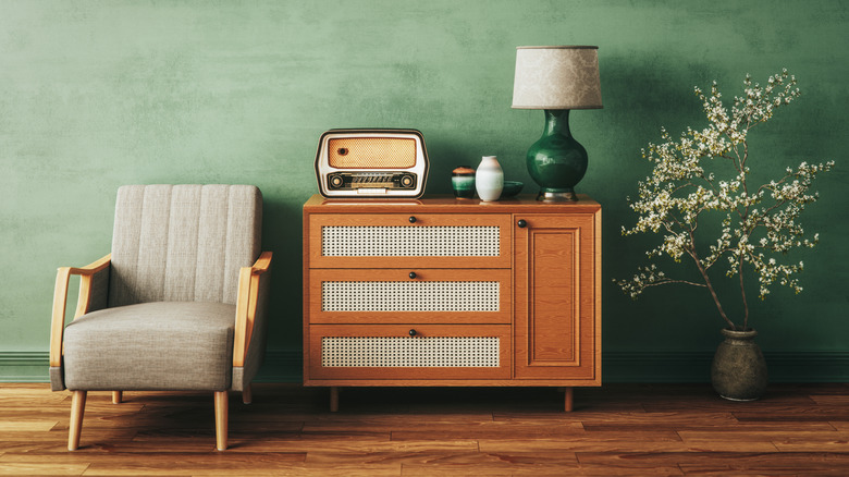 retro looking room with mid-century modern furniture, green paint, a branch in a jar, lamp, old-timey radio