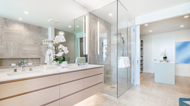 modern beige bathroom with glass shower and open access to an adjacent custom closet area with island