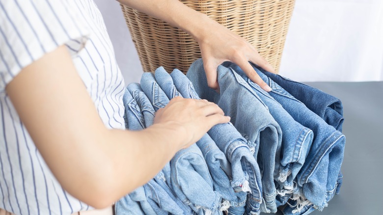 women with stack of folded jeans