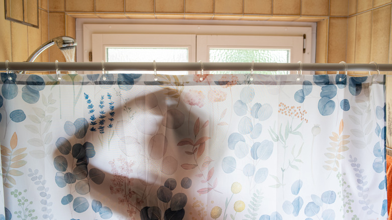 shadow of a person showering behind a shower curtain