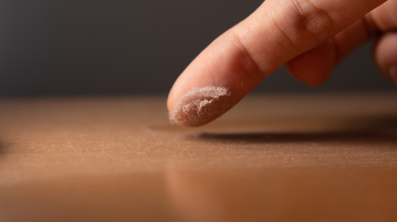 Finger touching a dusty table