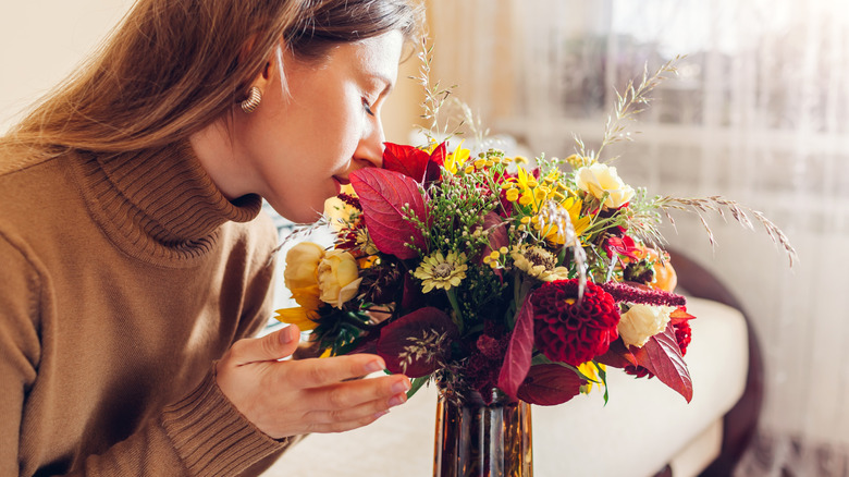 woman sniffing flowers in vase