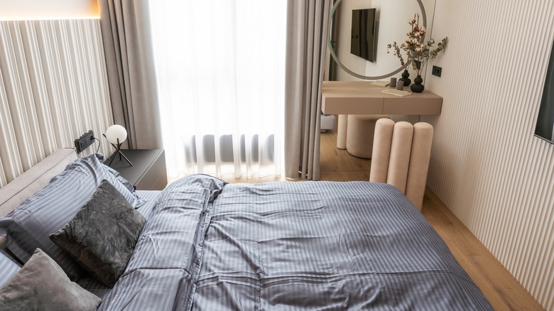 Dmall modern bedroom with queen bed, blue striped bedding, floor to ceiling window with gray drapes, black nightstand, and floating wood vanity