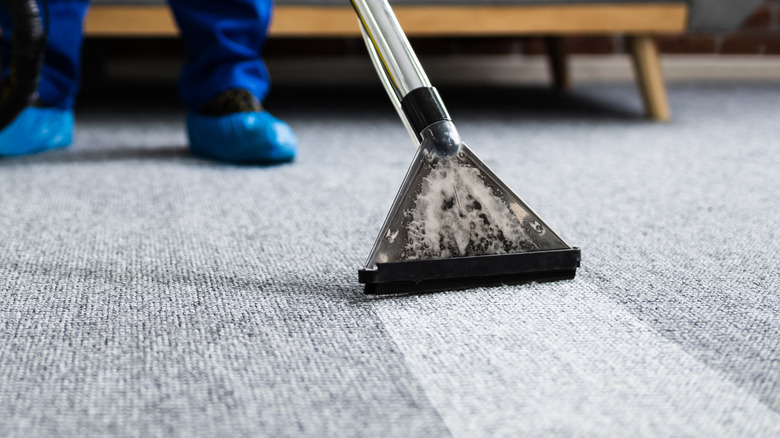 person shampooing gray carpet with a carpet cleaner