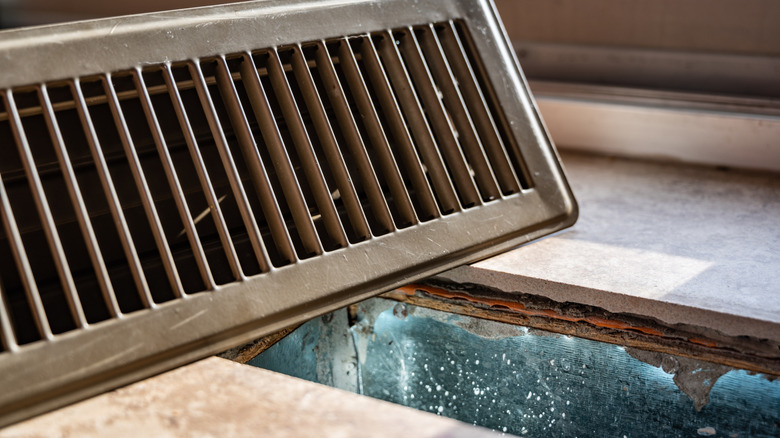 open brown floor HVAC register revealing ductwork beneath the floor