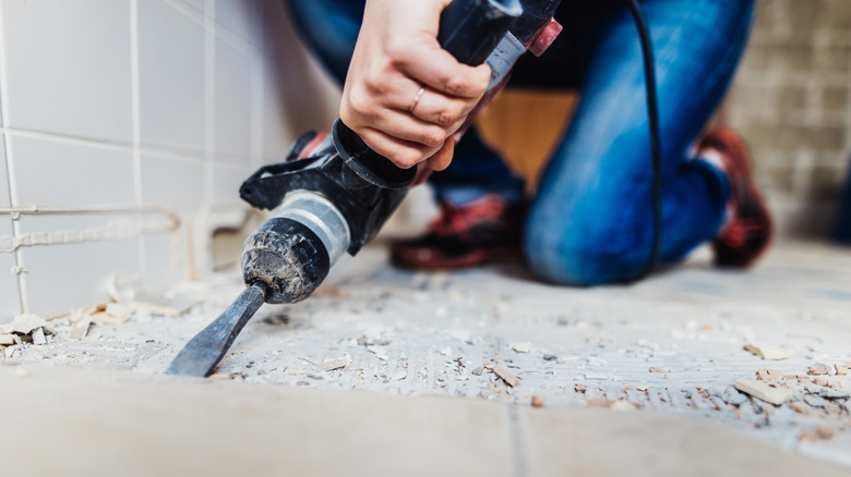 Woman removing old tiles in bathroom