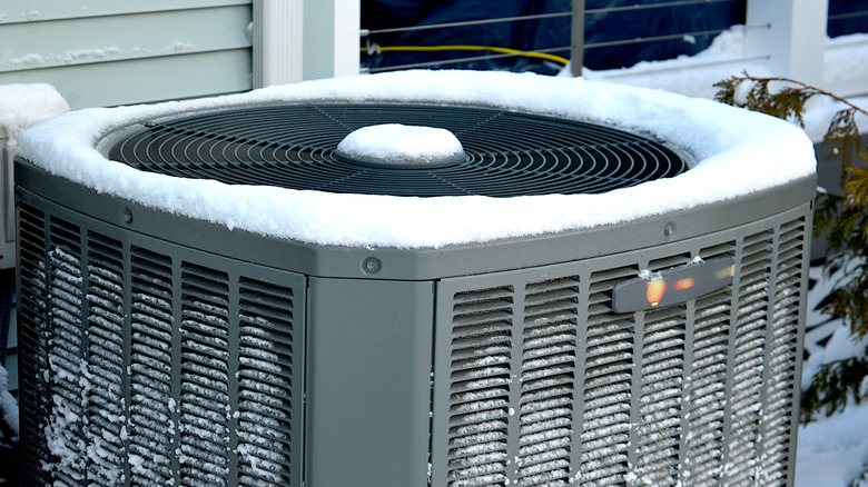 An outdoor air conditioning unit is covered with snow and ice.