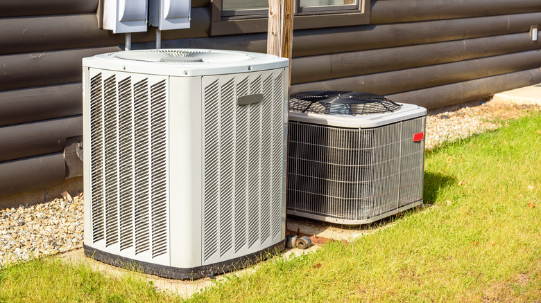 Outdoor heater and air conditioning units sit outside of a suburban house's foundation.