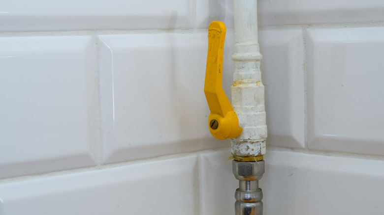 Open yellow gas line valve mounted to a wall