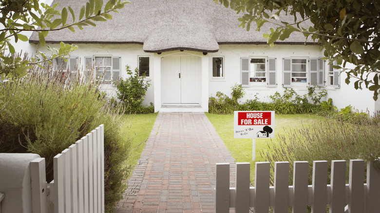 home with white fencing and for sale sign in yard