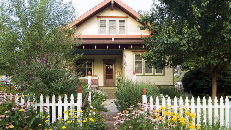 picture of the front of a home with white picket fencing and gorgeous flowers all around it